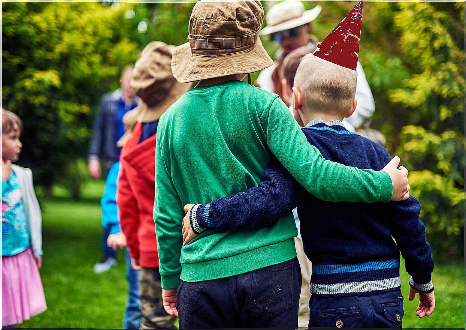 Friends hugging at a birthday party with classmates.