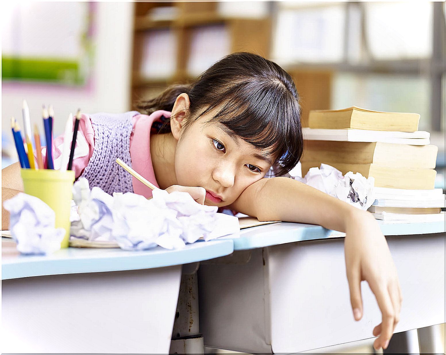 Girl sitting at school desk without motivation to learn.