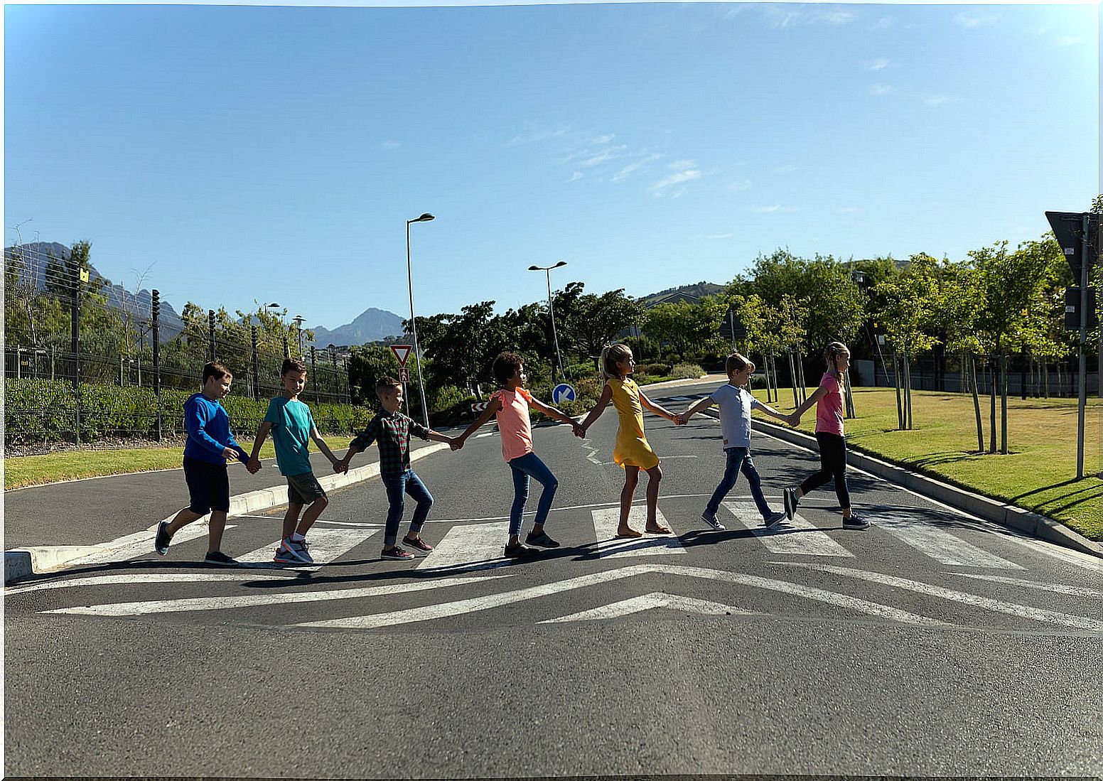 Children holding hands crossing a crosswalk.