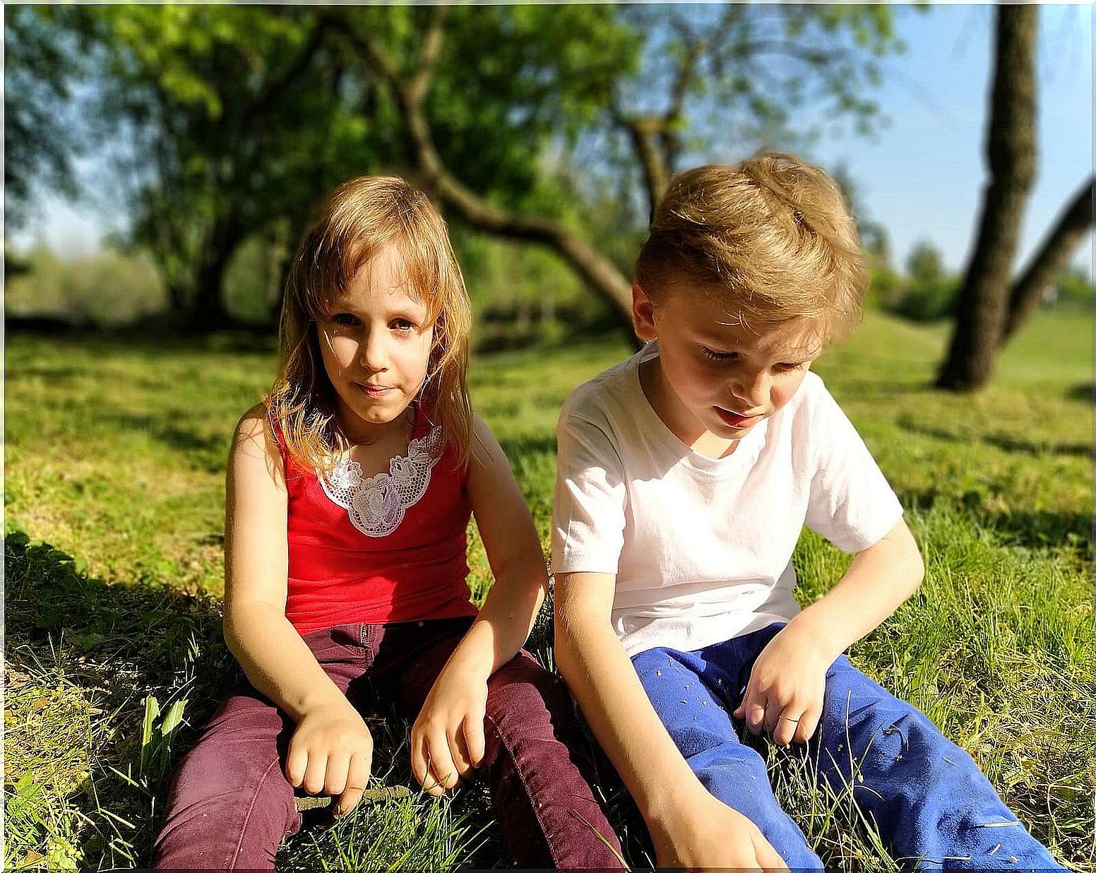 Friends sitting on the grass after playing as part of their social development.