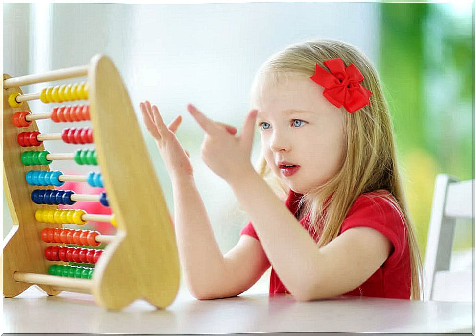 Girl learning to add with an abacus next to it thanks to the ABN method.