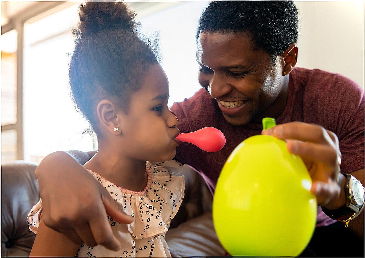 Father and daughter playing with balloons at home.