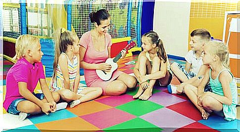 Children around teacher playing guitar in musical expression class.