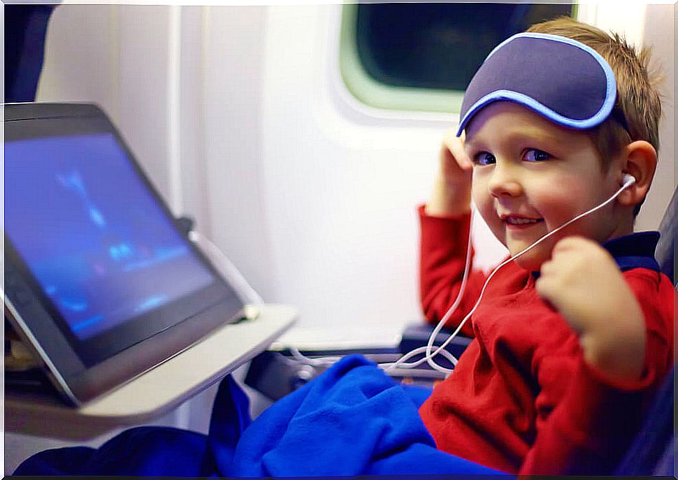 Boy watching a movie on the plane during his flight to go on vacation.