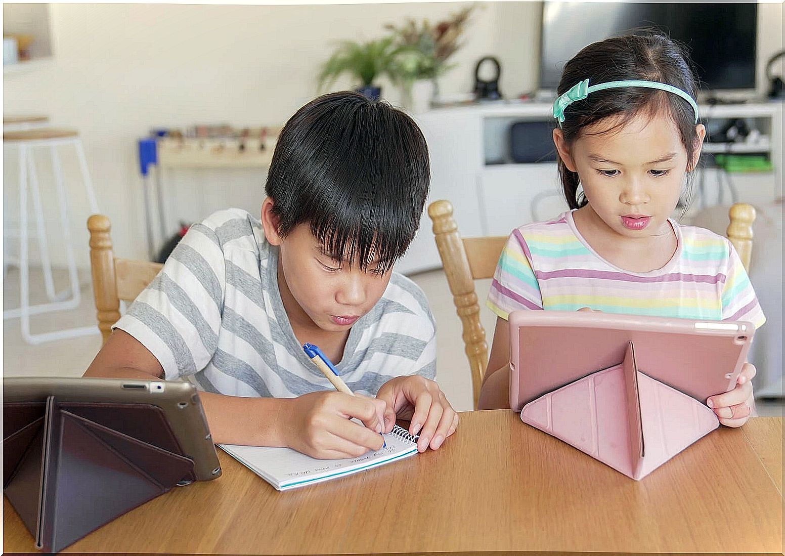 Child doing homework at home while listening to a podcast.