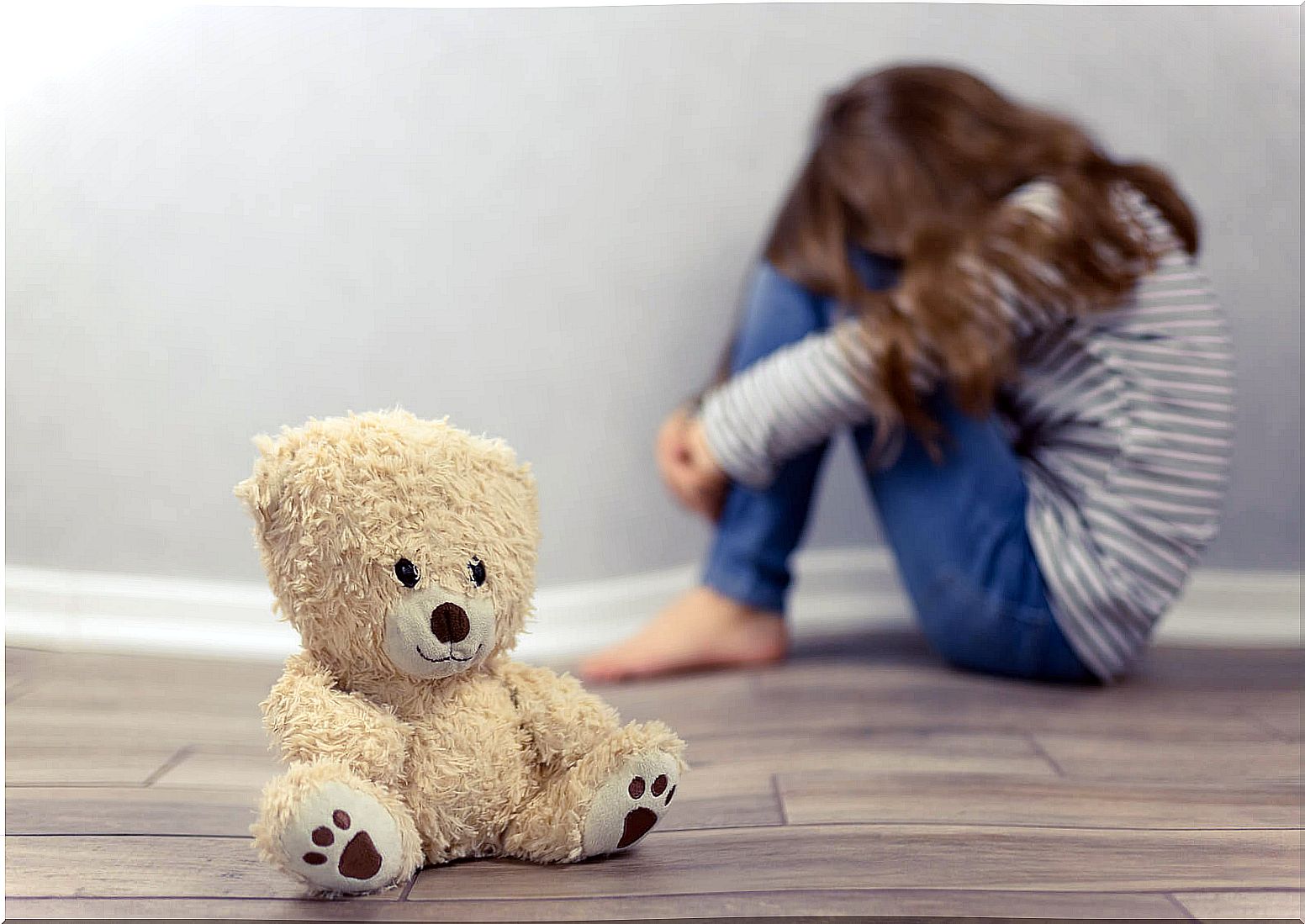 Very sad little girl with a teddy bear while thinking about suicide.