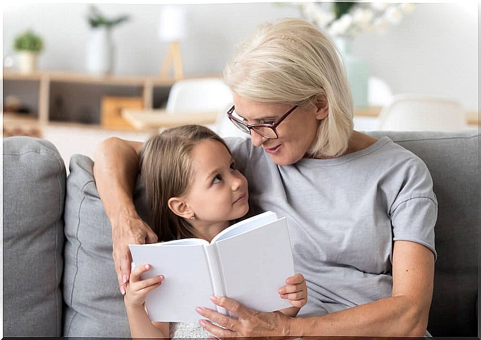 Grandmother reading one of the stories to learn spelling to her granddaughter.