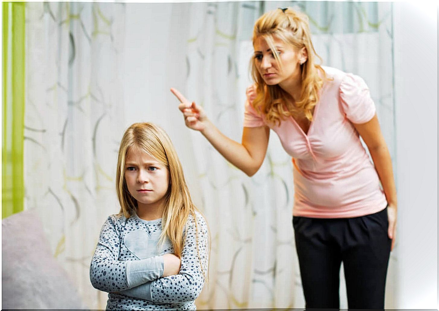 Mother with raised finger punishing her daughter.