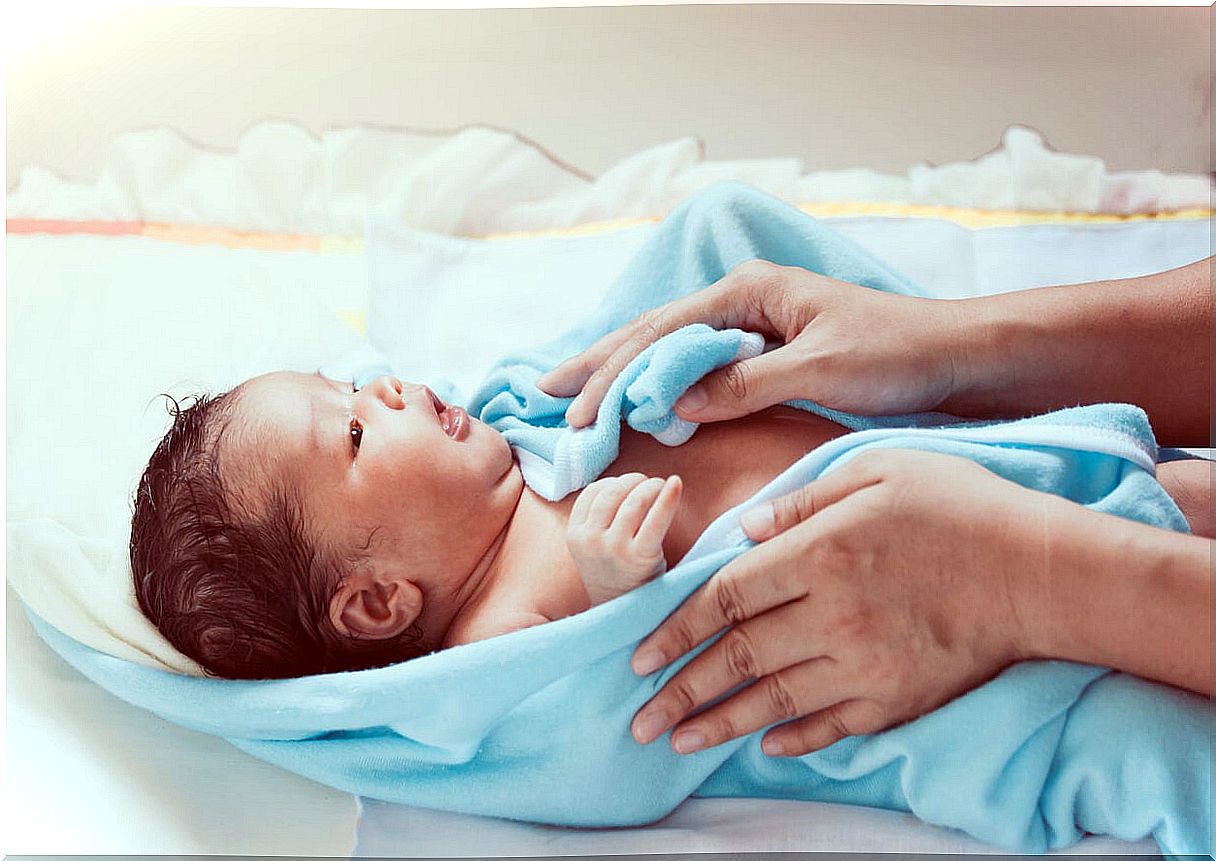 Newborn drying off with a towel after bathing.