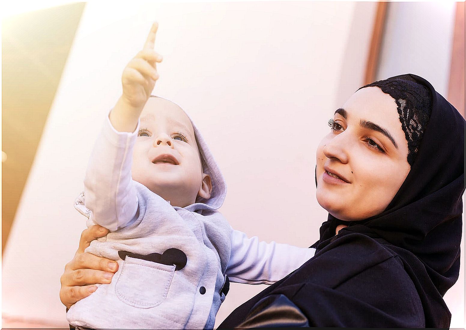 Mother with her son in her arms while pointing.