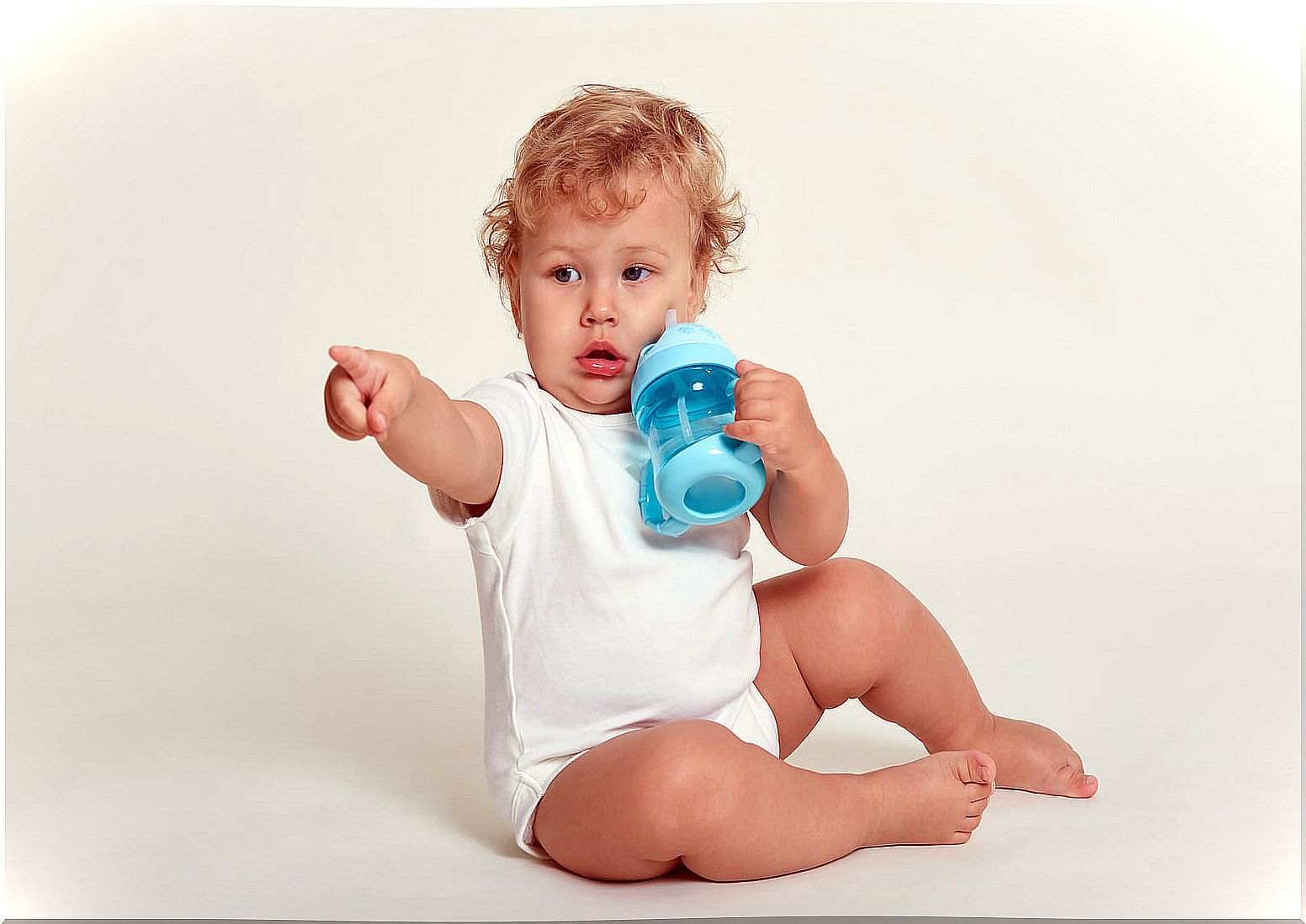 Child pointing with a bottle in his hand.