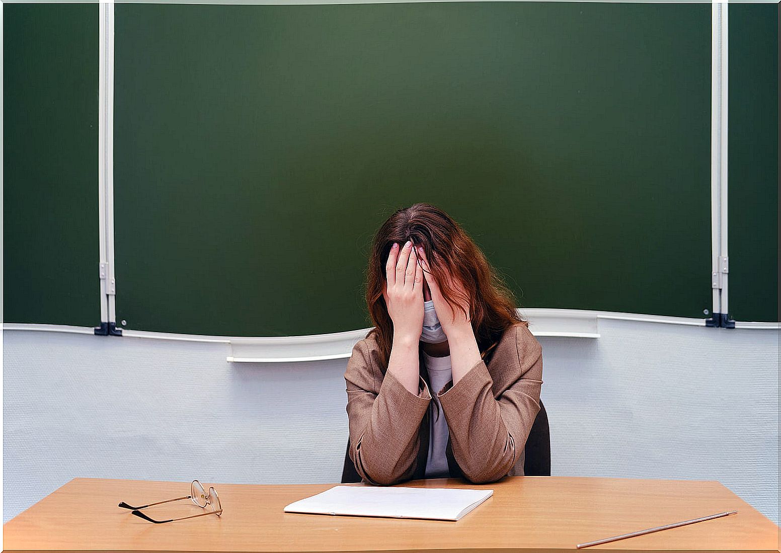 Teacher crying at the class table because she is bullied.