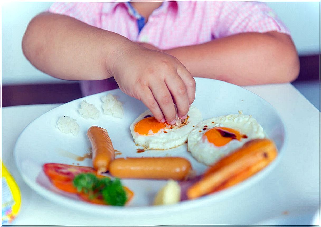 Child eating eggs with sausages.